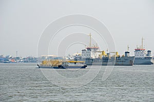 Cement container ship sails pass sand digger ships in Chao Phraya river