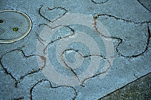Cement floor with hearts carved into wet pavement for design and pattern purposes in late afternoon shade
