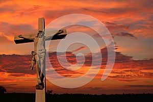 Cement life size cross with body of Jesus as sun sets