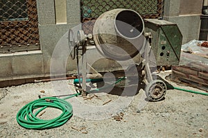 Cement mixer with hose and cement bags in a construction site