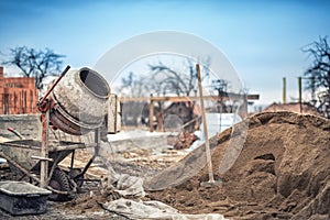 Cement mixer machine at construction site, tools and sand