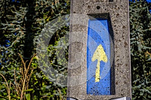 Cement post with a yellow arrow.