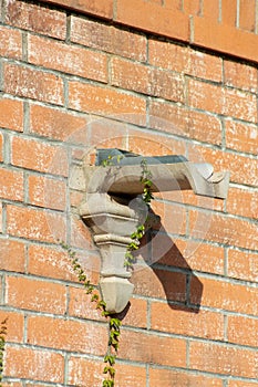 Cement rain gutter with metal slide on side of adobe red brick exterior of house or building in urban area of the city