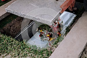 Cement slab was lowered to cover the coffin. Casket of the dead, with flowers from family and acquittances on top