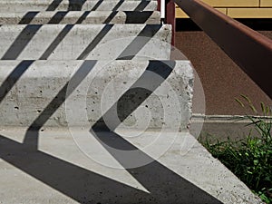 Cement stairs up. Sun shade. Brown handrail