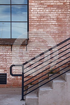 Cement steps and red brick wall with black handrail