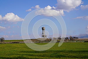 Cement water storage tank in a green grain field