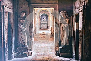 Cemetery corridor background with two statues in a vintage camera film effect look