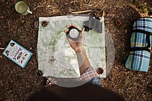 A girl is holding a compass to orientate in the forest with a map. photo