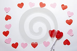 Cenital plane. White background with red and pink hearts with two heart-shaped lollipops. photo