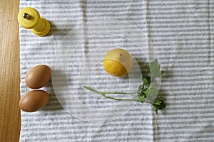 Cenital shot of 2 eggs, parsley, pepper shaker and a lemon photo