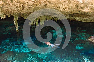 Cenote Dos Ojos in Quintana Roo, Mexico. People swimming and snorkeling in clear water. This cenote is located close to Tulum in photo