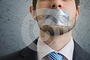 Censorship concept. Man is silenced with adhesive tape on his mouth