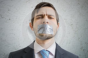 Censorship concept. Young man is silenced with duct tape over his mouth