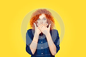 Censorship. Speak no evil concept. Concerned scared redhead woman curly afro hair covering her mouth with hands in blue jeans