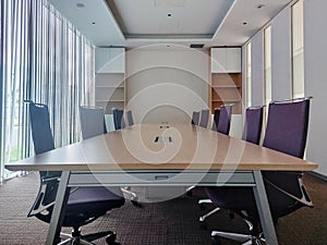 Center view of a meeting room with long wooden surface table and dark violet chair