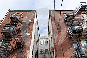 Centered view of a light well between apartment building wings, metal fire escapes, urban housing composition