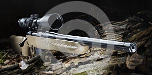 Centerfire bolt action rifle and scope in a dark forest
