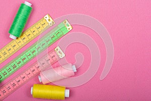 Centimeter and coils with threads of green, pink and yellow on a pink background
