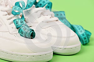 Centimeter in cyan blue color curled on white trainers