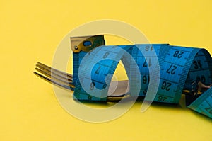 Centimeter and fork on a yellow background. Concept diet, healthy nutrition and weight loss
