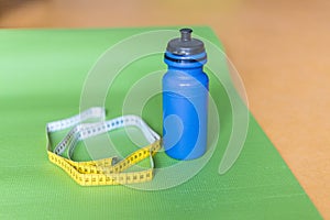 Centimeter tape, yoga mat and bottle of water at gym