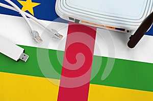 Central African Republic flag depicted on table with internet rj45 cable, wireless usb wifi adapter and router. Internet