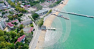 Central beach of Gelendzhik resort from a bird`s-eye view. Rows of sun loungers and umbrellas on the sand. People swim