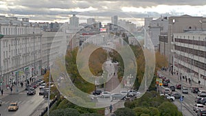 Central city street in rush hour with driving cars and green alley. Stock footage. Russia, Ekaterinburg, aerial view of