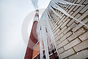 Central Heating and Power Plant with smoke industrial chimney  and icicles on the roof