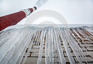 Central Heating and Power Plant with smoke industrial chimney  and icicles on the roof