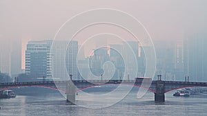 Central London City Skyline with iconic red London bus driving over Lambeth Bridge in blue misty fog