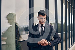 A CEO dressed in a sleek black suit stands confidently at the entrance of a modern corporate building, awaiting the