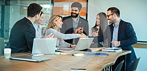 CEO female entrepreneur shaking hands with businessman while business partners clapping hands and celebrating in office
