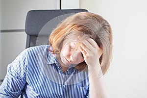 Cephalgia, migraine, headache, woman holds her head with her hand,suffers from pain at work in the office