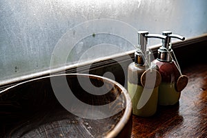 Ceramic bottles of shampoo and shower gel are placed in a large wooden bowl. And put on the wooden counter