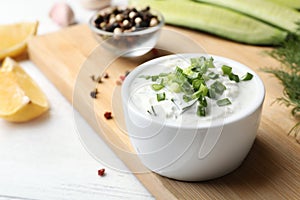 Ceramic bowl of cucumber sauce with ingredients on wooden table, space for text