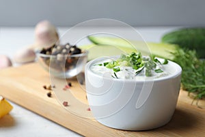 Ceramic bowl of cucumber sauce with ingredients on wooden table, space for text