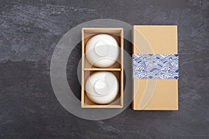 Ceramic bowl in paper gift box on black stone background