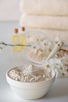 Ceramic bowl with white clay powder on white background. Ingredients for homemade facial and body mask or scrub