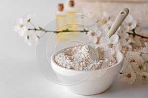 Ceramic bowl with white clay powder on white background. Ingredients for homemade facial and body mask or scrub