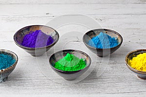 Ceramic bowls with Holi powder and copy space closeup on wooden