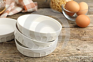 Ceramic casseroles and eggs on wooden table, closeup
