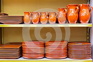 Ceramic crockery jugs and plates are on the store shelf.