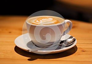 Ceramic cup in coffee shop with cappuccino on wooden empty table. Latte art. Morning drink. Caffeine.