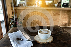 The ceramic cup of hot cappuccino coffee on the wooden table in the restaurant or coffee shop. natural light. morning hot drink