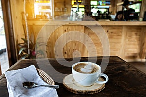 The ceramic cup of hot cappuccino coffee on the wooden table in the restaurant or coffee shop. natural light. morning hot drink