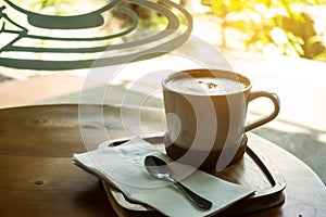 The ceramic cup of hot cappuccino coffee on the wooden table in the restaurant or coffee shop. natural light. morning hot drink