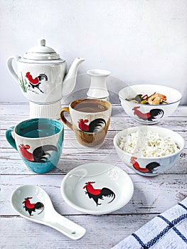 Ceramic cups, bowls, spoon, teapots and mugs with a picture of rooster on it