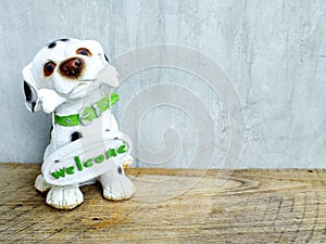 Ceramic dog with welcome sign on wooden background